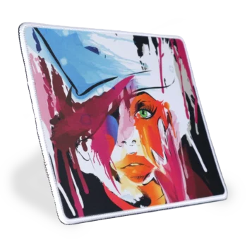 Zijaanzicht - gekanteld naar rechts - van een stoffen muismat met een witte gestikte rand met een abstract ontwerp. Het ontwerp bevat vlekken van rood, roze, zwart en blauw, wat een dynamisch en visueel opvallend patroon creëert. De achtergrond is zwart, waardoor de kleuren nog levendiger opvallen. Dit beeld is interessant vanwege het gedurfde kleurgebruik en de abstracte kunststijl, die verschillende interpretaties en emoties kan oproepen bij de kijkers.